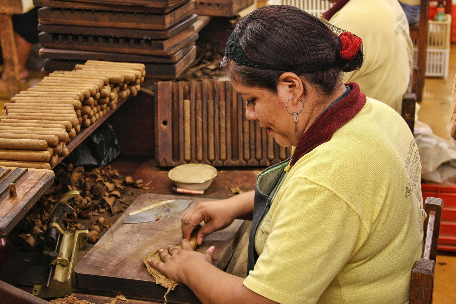 A woman expertly rolling cigars by hand in a Mexican factory, showcasing traditional craftsmanship.